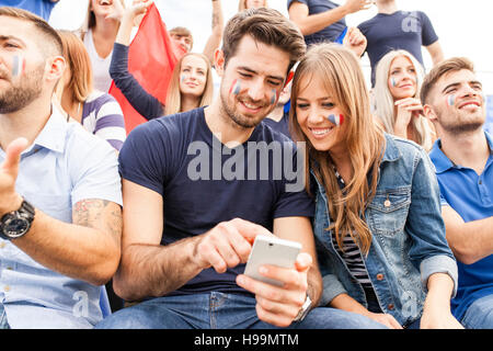 Gli appassionati di calcio con lo smartphone per la messaggistica di testo Foto Stock