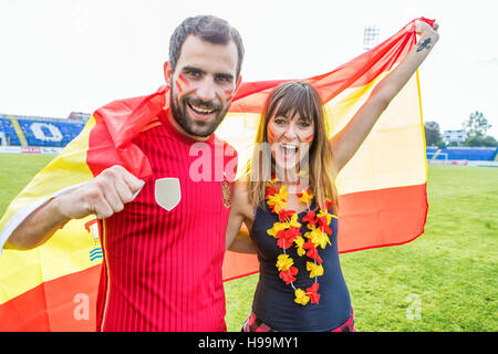 Coppia giovane con vernice faccia sventola bandiera spagnola Foto Stock