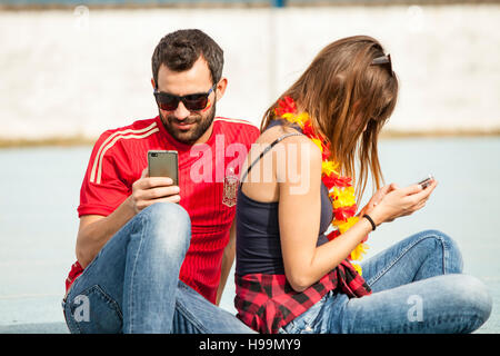 Coppia giovane in stadio di calcio seduta di schiena Foto Stock