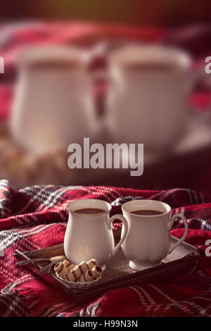 Vassoio di cioccolate calde sul tappeto di tartan con la stessa immagine sfuocata in background - utile per il concetto di pubblicità Foto Stock