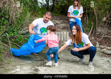 La famiglia e i volontari facendo pulizia di immondizia in posizione di parcheggio Foto Stock