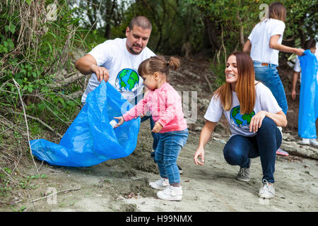 La famiglia e i volontari facendo pulizia di immondizia in posizione di parcheggio Foto Stock