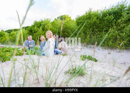 Gruppo di amici seduti sulla spiaggia sabbiosa Foto Stock