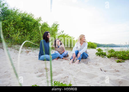 Il gruppo di donne seduto sulla spiaggia sabbiosa Foto Stock