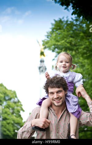 Ragazza sulle spalle dei padri con Friedensengel monumento in background Foto Stock