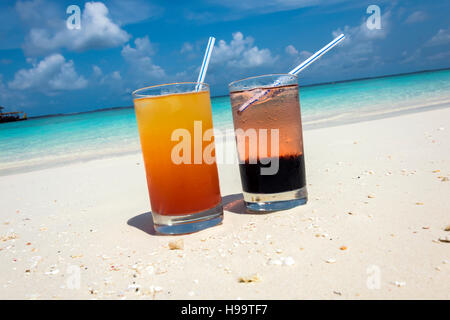 Due cocktail colorati recante sulla sabbia bianca, piccoli coralli spiaggia coperta di fronte all'incredibile acqua turchese dell'indiano oc Foto Stock