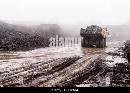 Un Terex rock dumper assume un pieno carico di pietra in una cava in heavy rain. Foto Stock