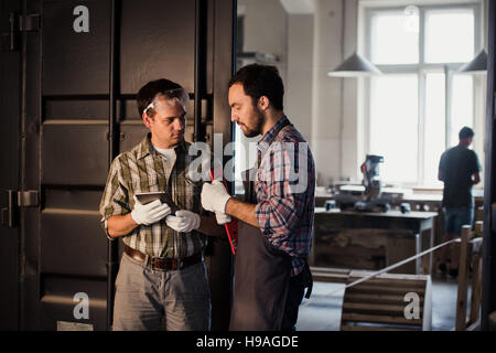 Professione, tecnologia e concetto di persone - due operai con tablet pc computer in officina Foto Stock