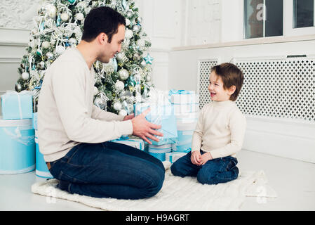 Padre e figlio scartare un presente sdraiato sul pavimento Foto Stock