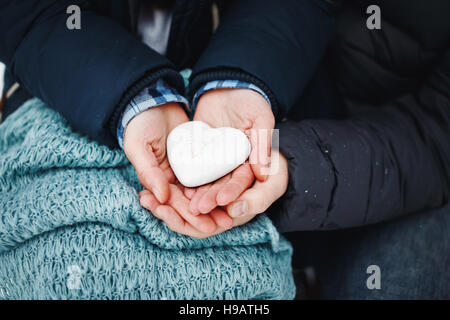 L uomo e la donna mani tenendo lo zenzero pane cuore in bianco ghiaccio, close-up. Il giorno di San Valentino vacanza. Foto Stock