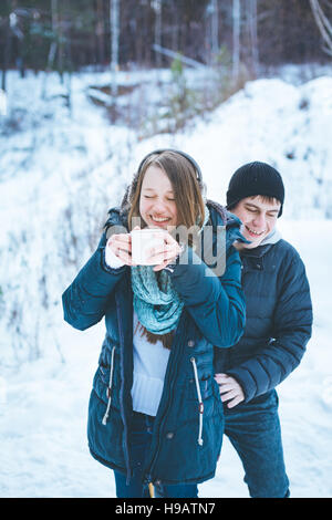 Amare giovane avendo divertimento all'aperto in inverno, bere una bevanda calda Foto Stock