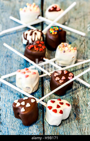Molti POP di torta a forma di cuore giacciono sul vecchio blu sullo sfondo di legno vista dall'alto. Foto Stock