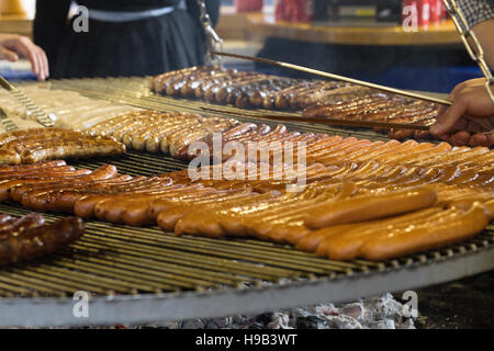 Ranghi di tedesco salsicce bratwurst essendo tendeva sul grande grill, street cibo al mercato di Natale Foto Stock