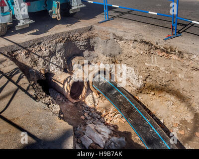 In plastica nuova canalizzazione fognaria essendo inserita in un cast rotto tubo di ferro. Foto Stock
