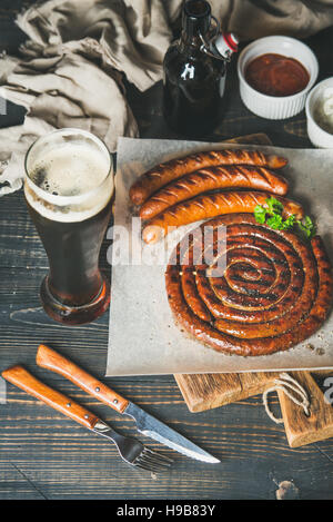 Bicchiere di birra e salsicce alla griglia su legno scheda servente Foto Stock