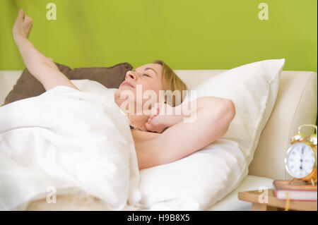 Giovane donna nel letto, dopo il risveglio Foto Stock