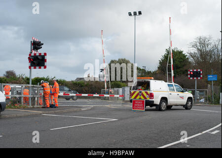 Rete ingegneri ferroviari la riparazione di un passaggio a livello ferroviario barriera dopo la parte di essa si è rotto a causa di forti venti. Foto Stock