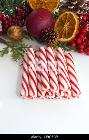 Stick menta piperita candy canes impilati su un bianco sfondo isolato con festa di Natale decorazioni in background Foto Stock