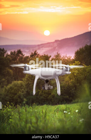 In bilico drone a scattare foto di natura verde al tramonto Foto Stock