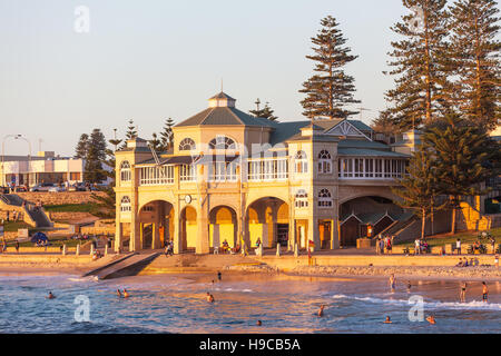 Nuotatori rilassante e di balneazione al tramonto di fronte al vecchio iconica pavillion a Cottesloe Beach a Perth, Western Australia. Foto Stock