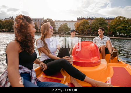 Inquadratura di gruppo di giovani seduti sul pedale barca nel lago. Amici di adolescenti godendo sul pedale barca nel lago. Foto Stock
