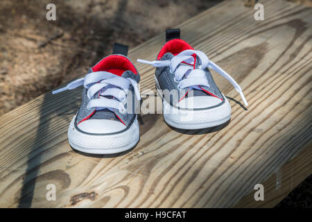 Coppia di toddler sneakers su una panca in legno all'esterno Foto Stock