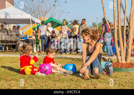 Giovane donna guarda i suoi figli guardando attraverso le loro zucche di plastica riempiti con la caramella a un trunk o trattare fall festival presso una chiesa battista in MS Foto Stock