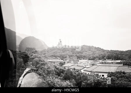 Vista del Big Buddha sull'Isola di Lantau dalla Cabinovia di Ngong Ping con la riflessione del passeggero / Hong Kong / immagine in bianco e nero Foto Stock