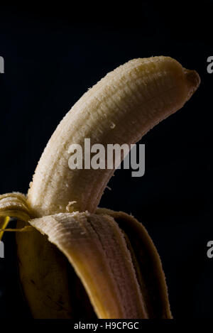 Organici e banana pelata su uno sfondo nero. Foto Stock