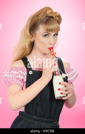 Pin Up girl bere latte da un retrò swing top bottiglia con cannucce Foto Stock