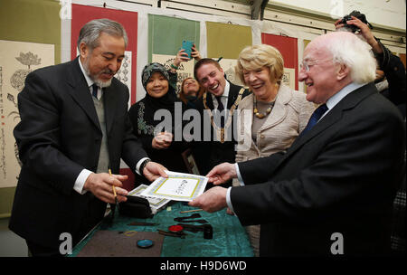 Presidente irlandese Michael D Higgins (destra) presenta maestro calligrafo Haji Noor Deen Mi Guang Jiang (sinistra) con qualche lingua irlandese calligrafia, come il Presidente la moglie Sabina Coyne (seconda a destra) e Cormac Devlin, Cathaoirleach di Dun Laoghaire Rathdown County Council a guardare, durante una visita al Centro Culturale Islamico di Irlanda, Clonskeagh, Dublino il suo ventesimo anniversario. Foto Stock