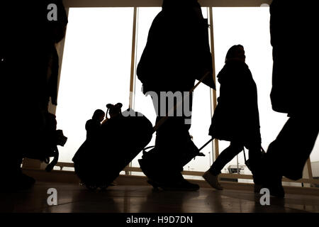 Sagome di persone a piedi con i bagagli in un aeroporto Foto Stock