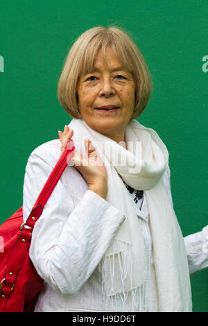 Senior lady giapponese pone in un elegante mantello bianco con rosso borsa a tracolla Foto Stock