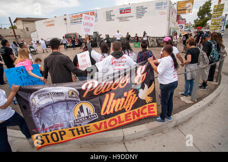 Local ispanici unire le mani in un cerchio in Santa Ana CA in un rally contro la violenza di strada nella Comunità. Nota banner con segno. Foto Stock