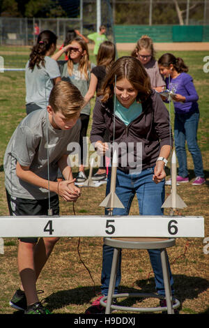 Multirazziale Mission Viejo, CA, middle school gli studenti a prepararsi per il lancio di una polvere nera di razzi come parte del loro programma di studi scientifici. Nota numerata rotaie di lancio. Foto Stock