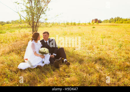 Giovane sposa e lo sposo sul campo dello sfondo. Foto Stock