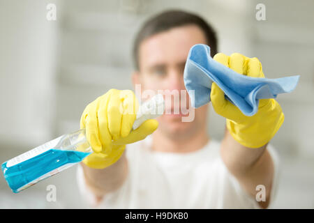 Primo piano dei maschi di mani guanti in azienda e spray rug Foto Stock
