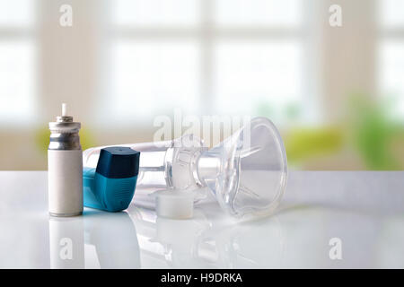 Cartuccia, medicina blu inalatore, camera di inalazione e maschera di silicone bianco sul tavolo di vetro in una stanza. Vista frontale. Composizione orizzontale Foto Stock