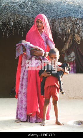 Una famiglia al di fuori della loro casa di fango nelle colline di Bhenswara, una piccola comunità agricola al di fuori di Jodphur, India. Foto Stock