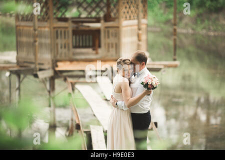 Lo sposo baci la sposa di fronte mentre lei si appoggia a lui sorridente Foto Stock