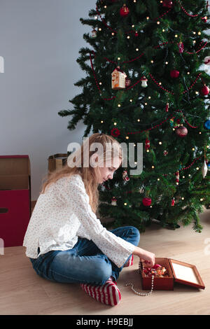 Ragazza giovane decorare albero di Natale a casa Foto Stock