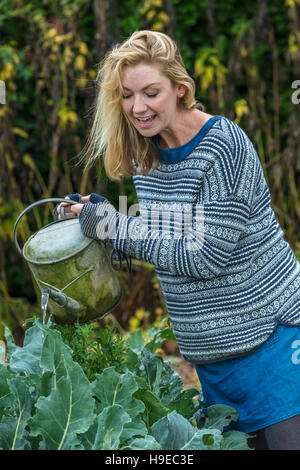 Persone di mezza età donna bionda coltivazione degli ortaggi giardinaggio con annaffiatoio Foto Stock
