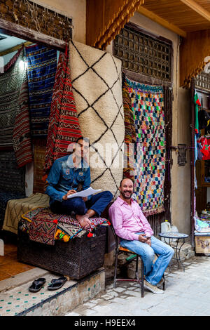 Due venditori di tappeti al di fuori del loro negozio nella Medina di Fez, Marocco Foto Stock