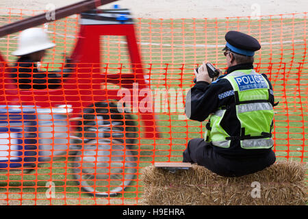 La polizia del sostegno comunitario Officer utilizza la pistola radar per misurare la velocità di passaggio in discesa soap box Foto Stock