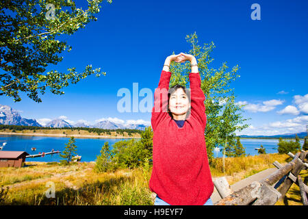 Sorridente donna giapponese bracci di estensione vicino al lago Foto Stock