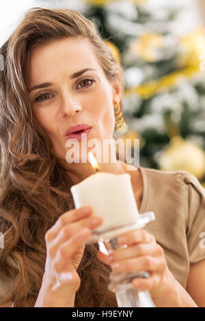 Giovane donna soffiando candela nella parte anteriore dell albero di natale Foto Stock