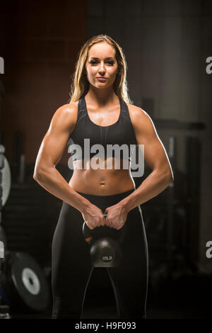 La donna caucasica kettlebell sollevamento in palestra Foto Stock