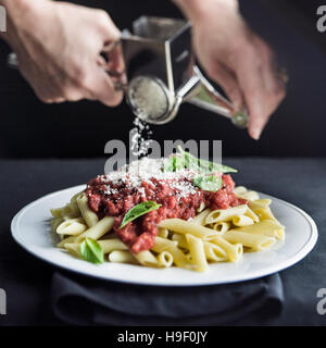 Reticolo di mani parmigiano sulla pasta penne Foto Stock