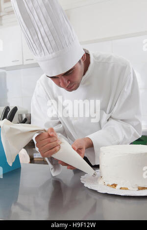 Lo chef ispanica decorare la torta Foto Stock