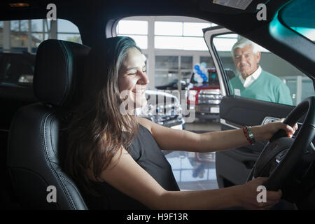 Ispanico donna seduta in auto in concessionaria showroom Foto Stock